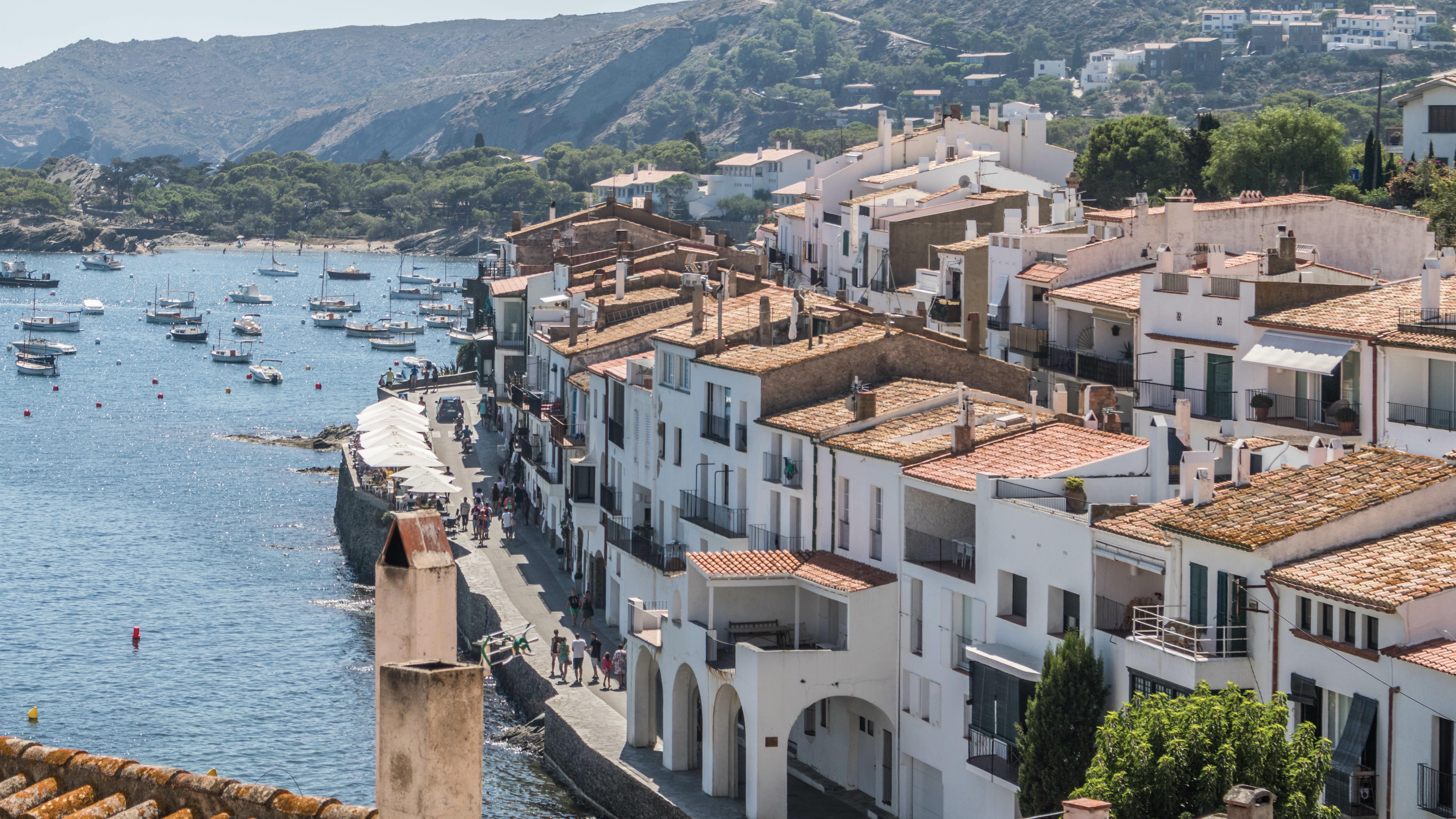Vue sur les façades blanches de la ville de Cadaqués en bord de mer avec les collines verdoyantes au loin