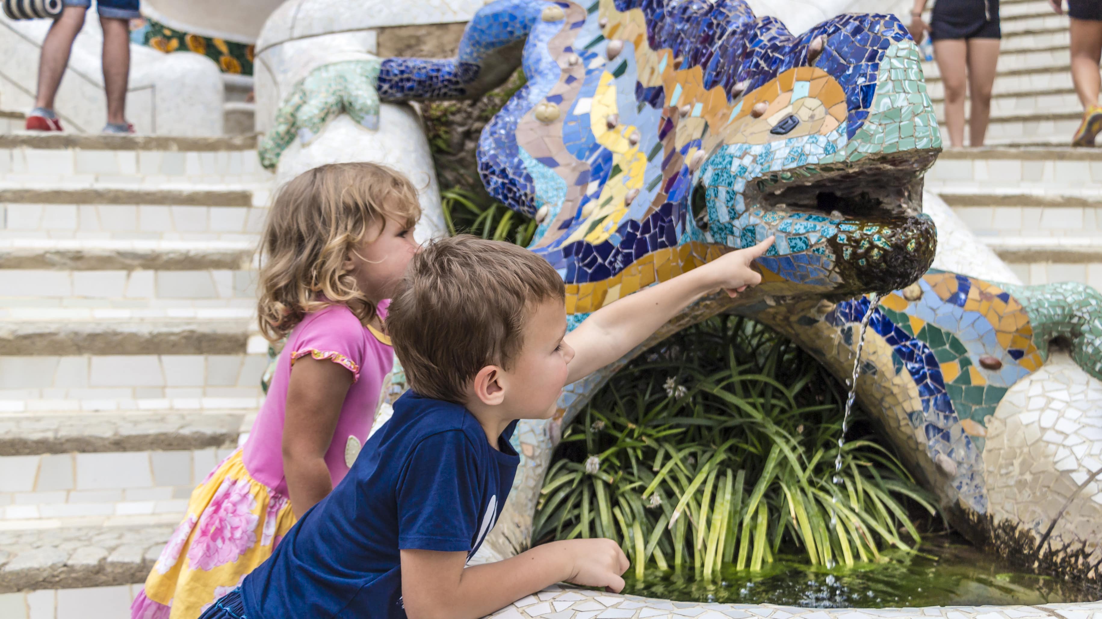 Deux enfants devant un lézard en mosaïques colorées au parc Güell à Barcelone