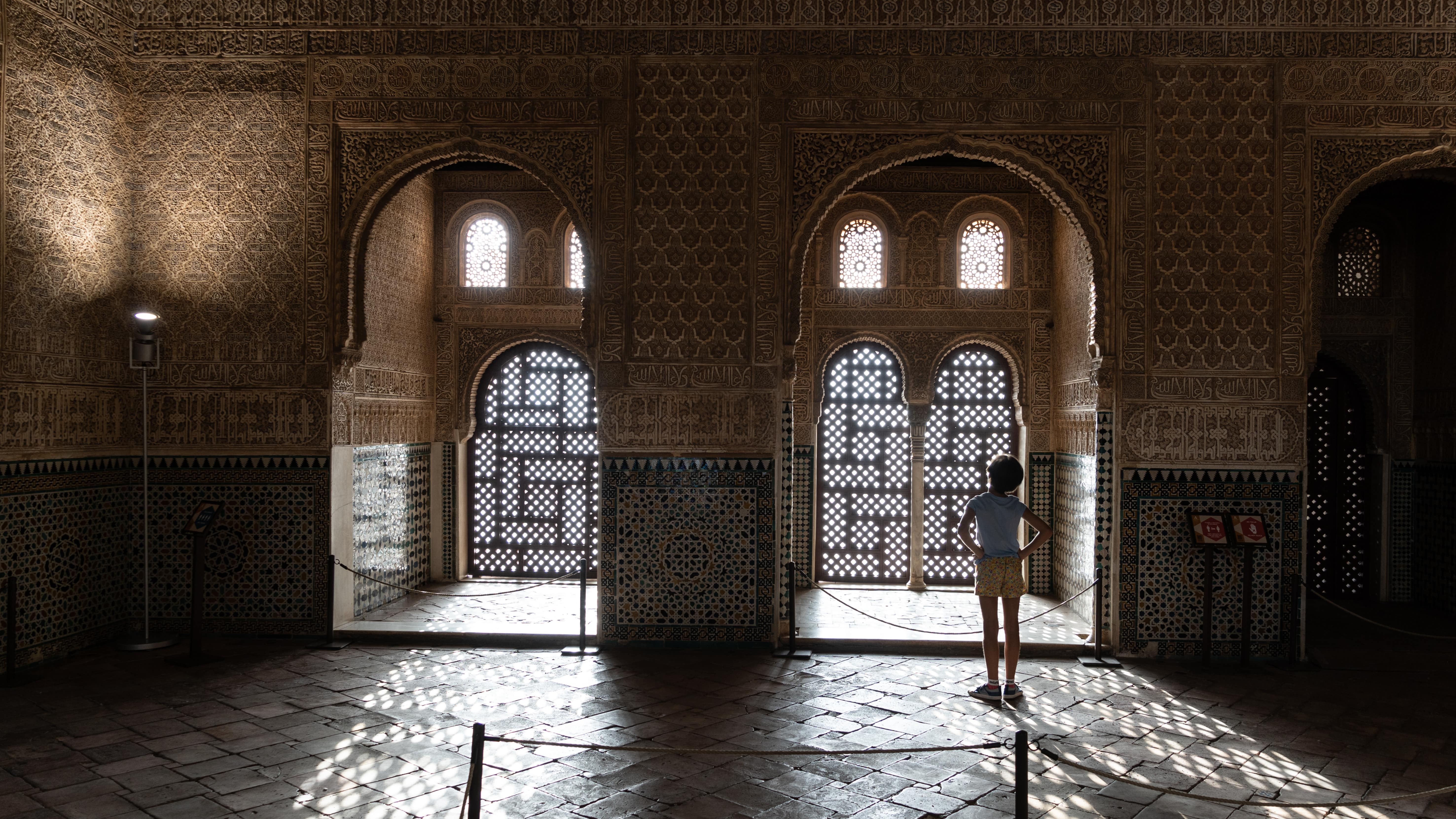 Une fillette de dos, observant un moucharabieh à l’Alhambra de Grenade