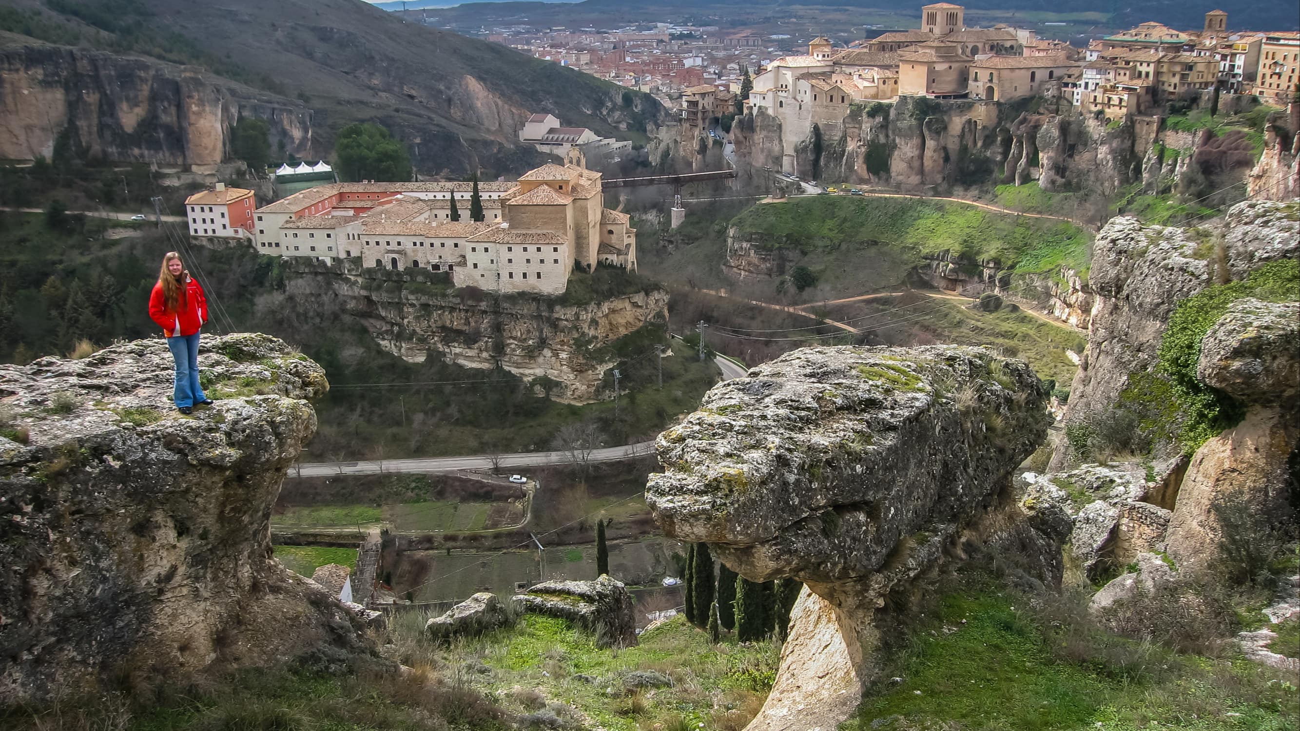 Jeune fille sur un promontoire rocheux avec vue sur la ville médiévale de Cuenca