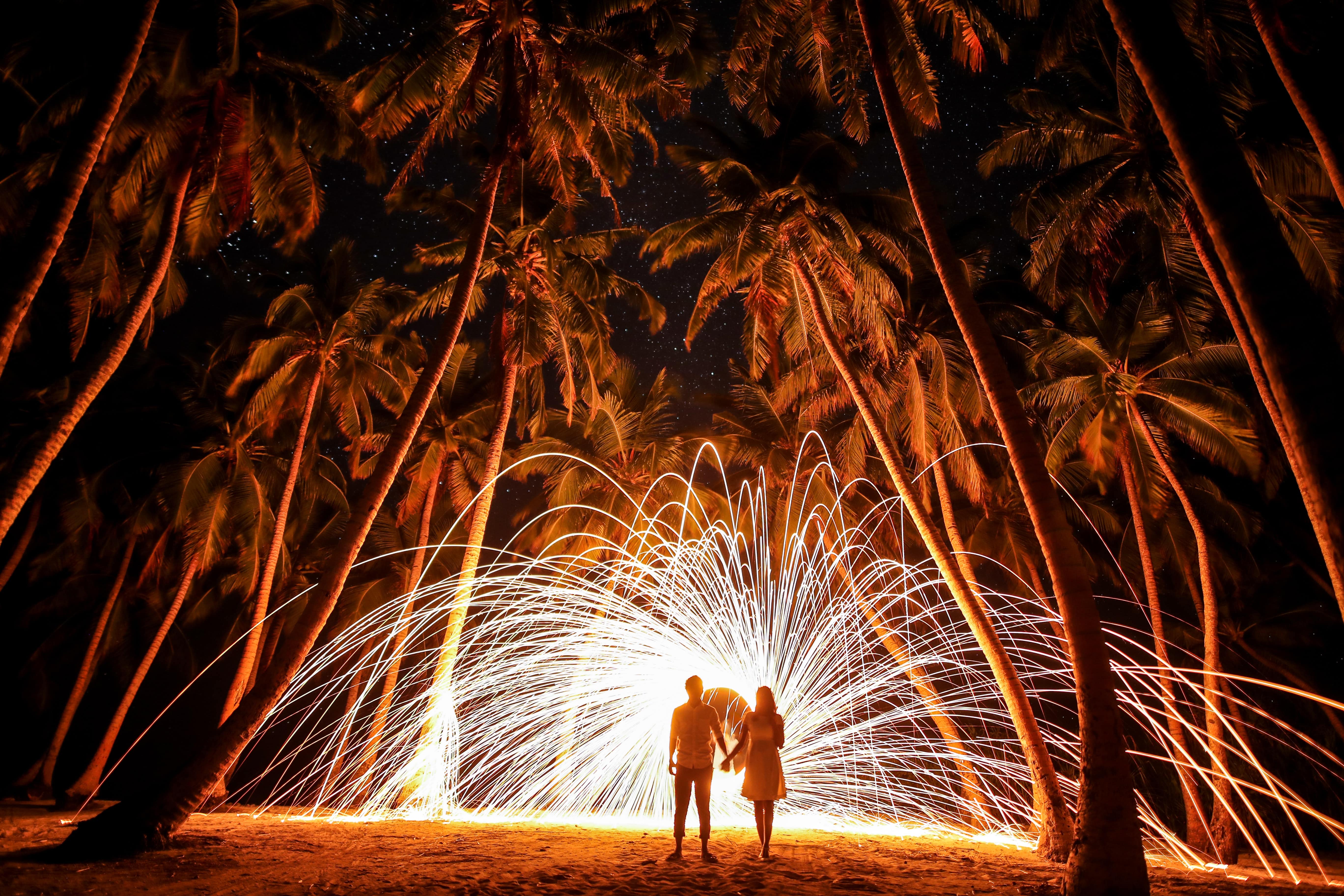 Couple watching fireworks under palm trees STOCK